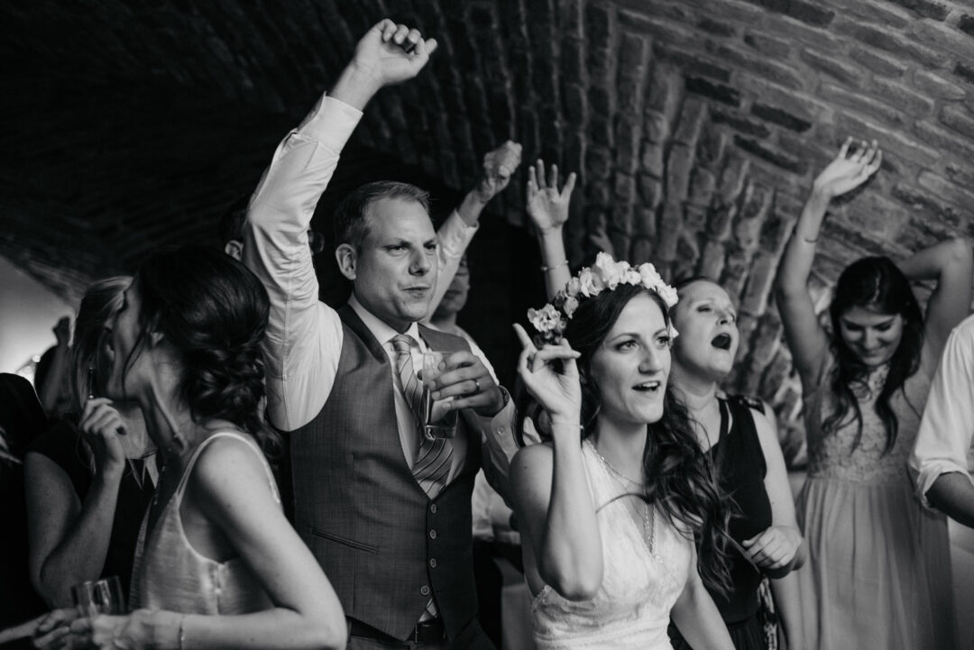 Brautpaar und Gäste feiern mit erhobenen Händen