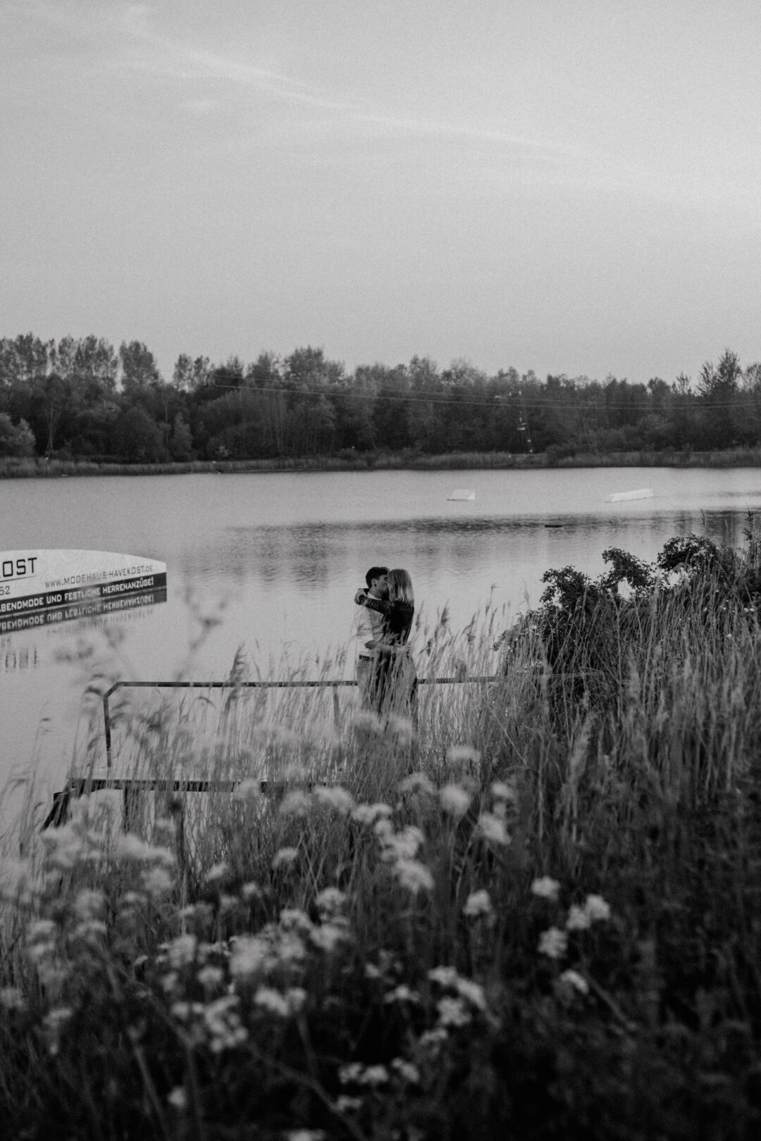 Paar steht zwischen Blumen am Wasserufer