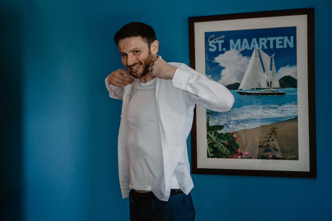 Freund zieht sich vor blauer Wand ein Hemd an