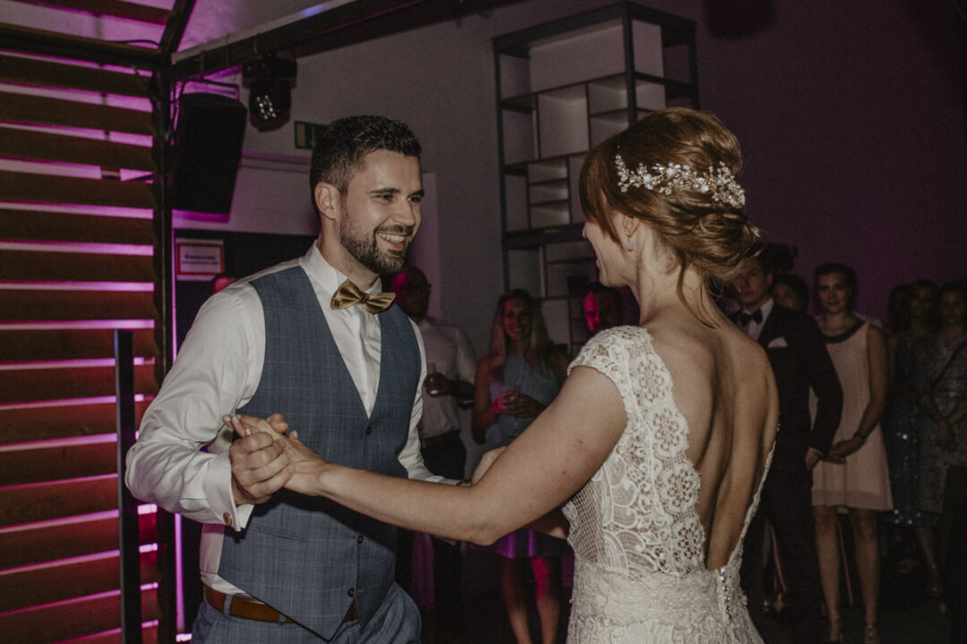 Erster Hochzeitstanz des Brautpaares mit Gästen im Hintergrund