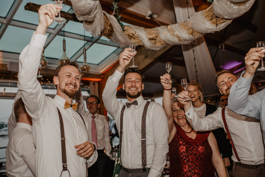 Gäste jubeln mit erhobenen Gläsern