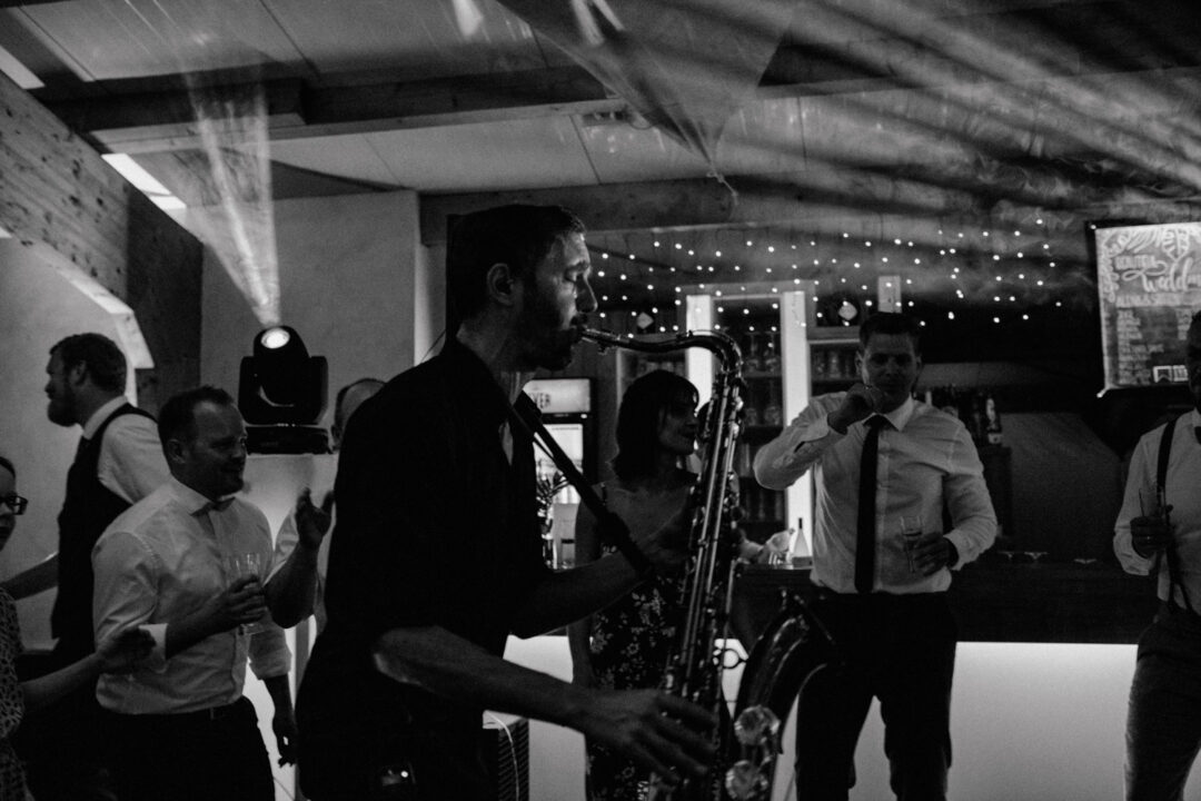 Tanzfläche mit DJ, Saxophonist und feiernden Gästen