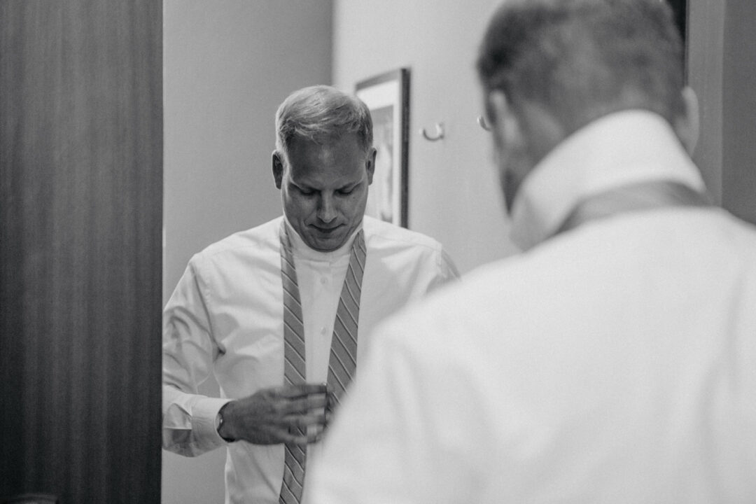 Mann bindet Krawatte vor dem Spiegel