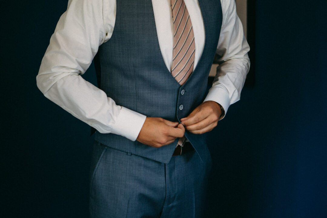 Bräutigam knöpft Weste seines Hochzeitsanzugs