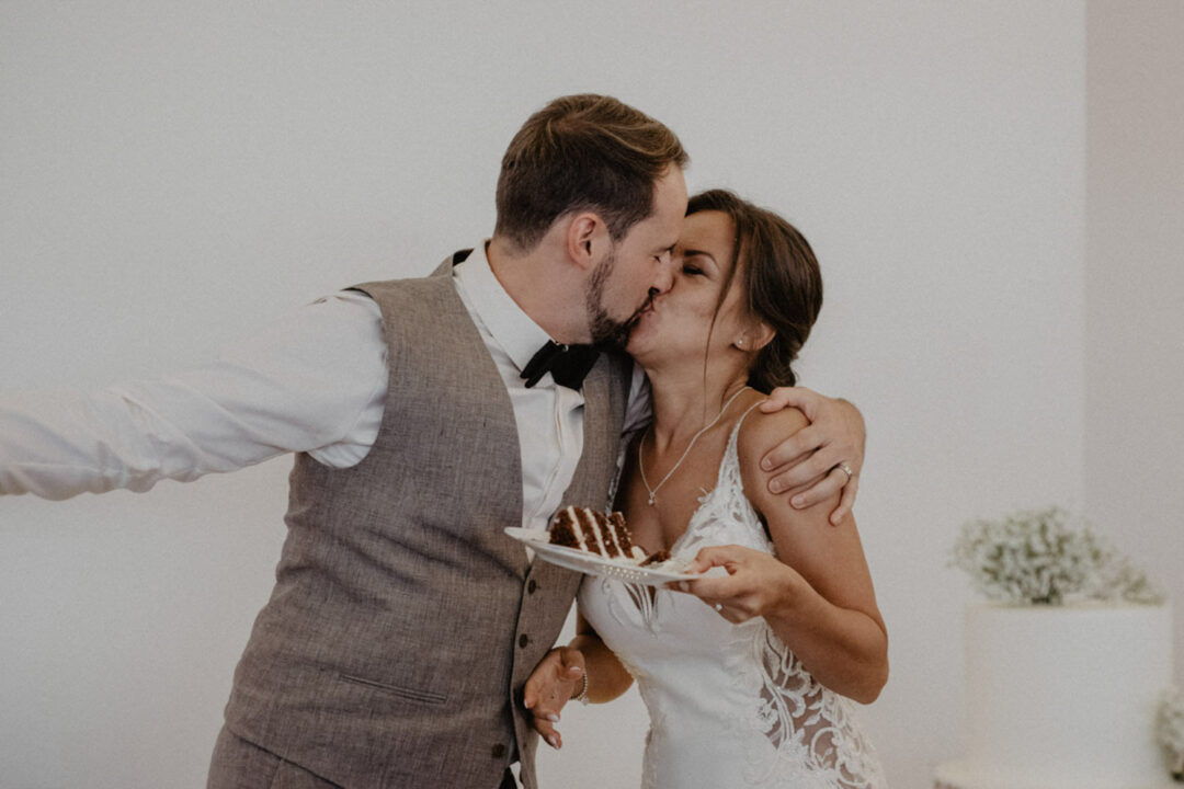 Brautpaar küsst sich nach dem Tortenanschnitt