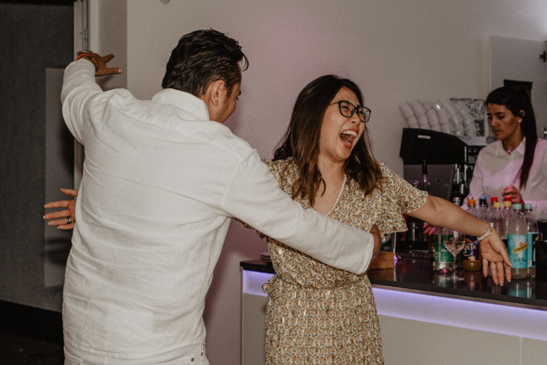 Gäste tanzen lachend an der Bar mit Seeblick