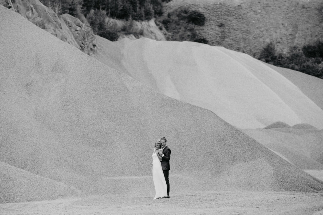 Das Paar steht allein in weiter, sandiger Landschaft