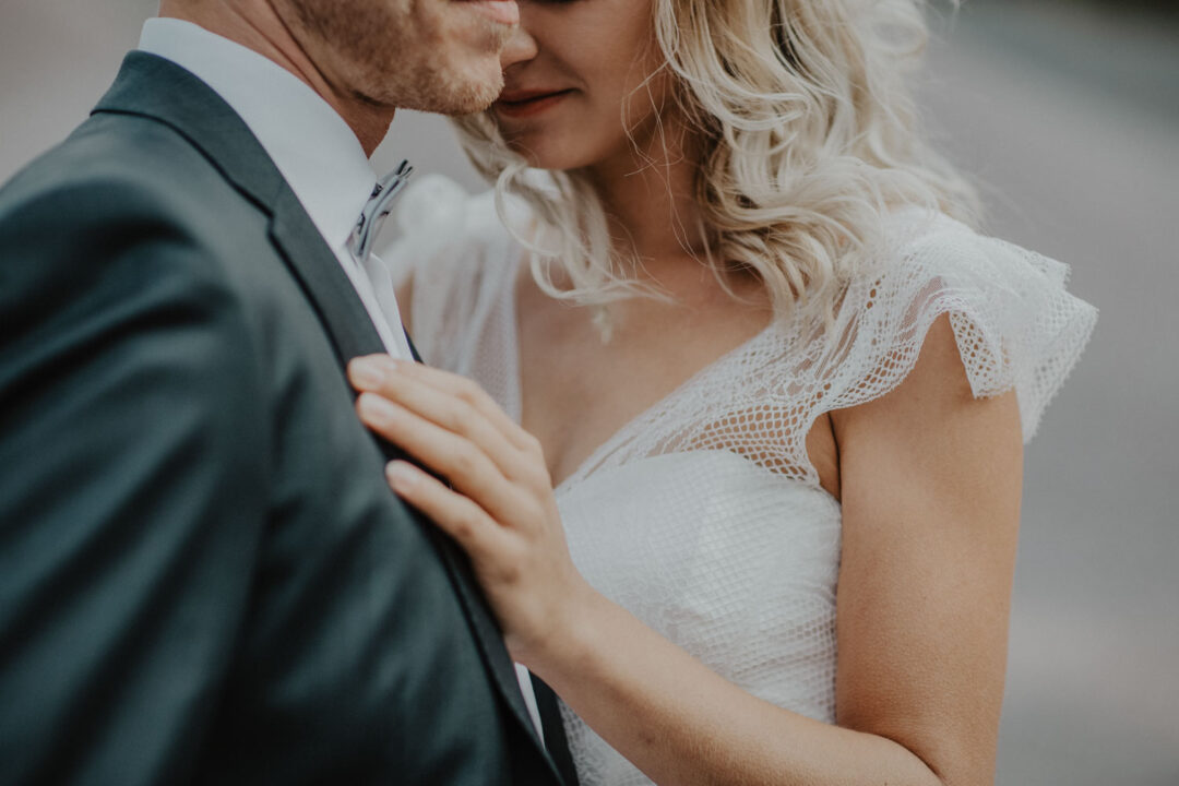 Nahaufnahme der Umarmung, Hände der Braut ruhen auf dem Anzug