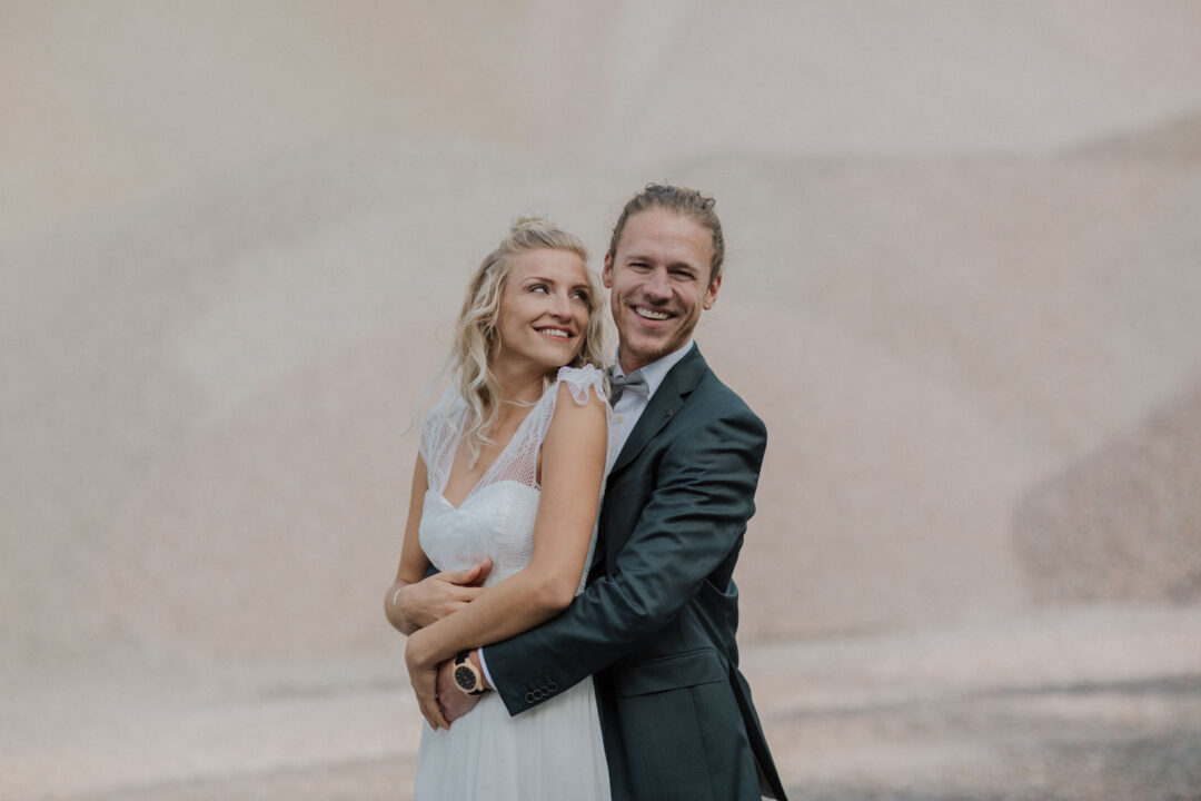 Braut lehnt sich an Bräutigam in offener Kulisse