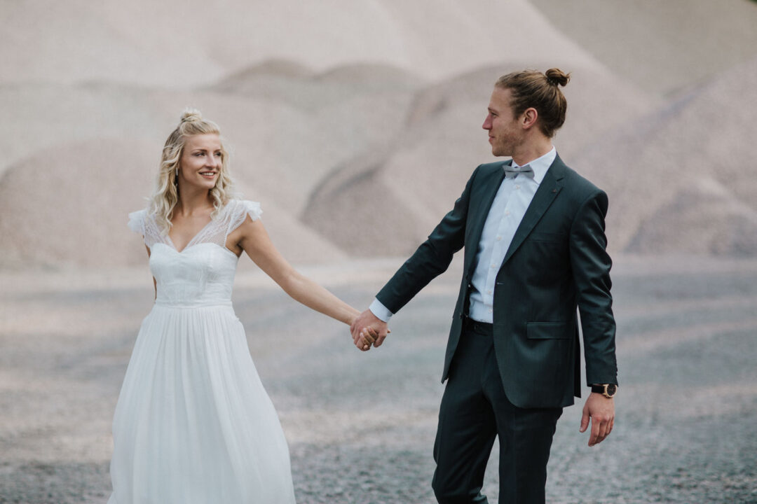 Braut und Bräutigam gehen Hand in Hand durch die Kulisse