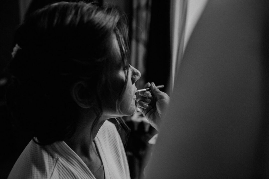 Braut beim Lippen-Make-up, Schwarz-Weiß-Aufnahme