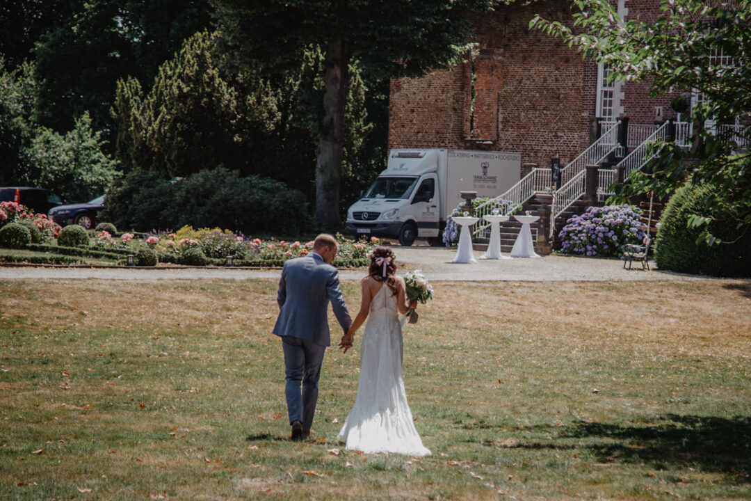 Brautpaar Hand in Hand auf dem Weg zur Feier