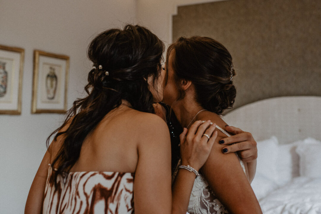 Braut und Trauzeugin umarmen sich innig