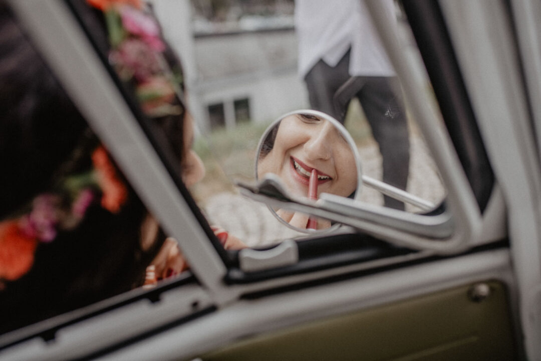 Braut trägt Lippenstift im Rückspiegel auf