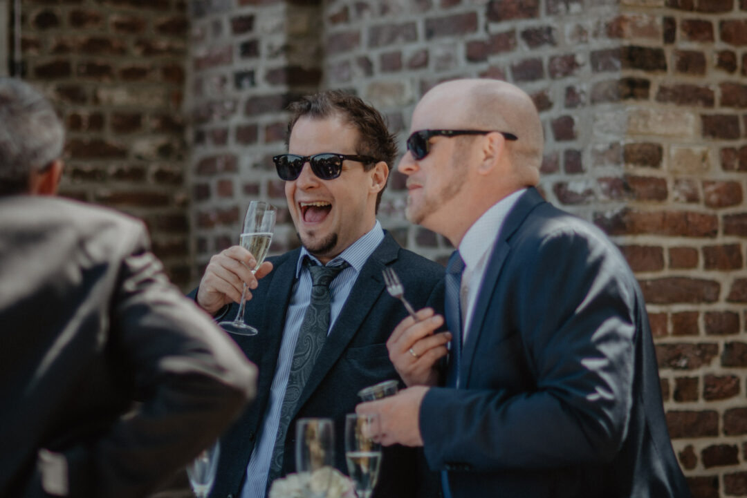 Hochzeitsgäste lachen bei einem Glas Sekt