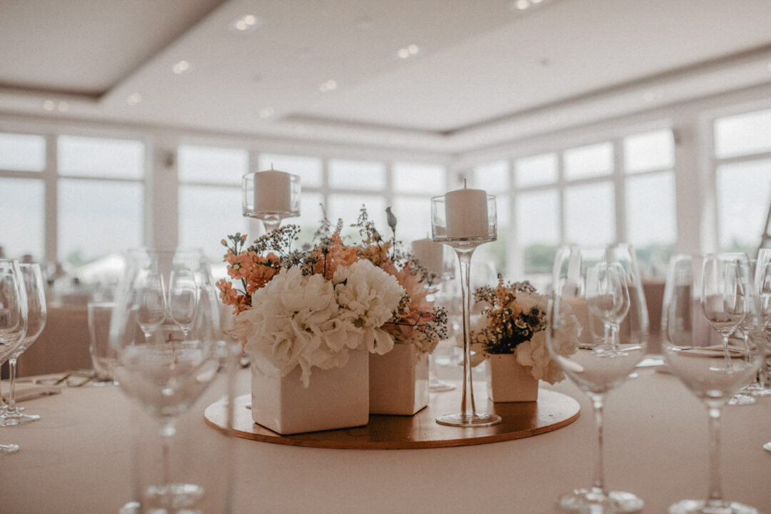 Weiße Blumen und Kerzen als Tischdeko bei Tageslicht