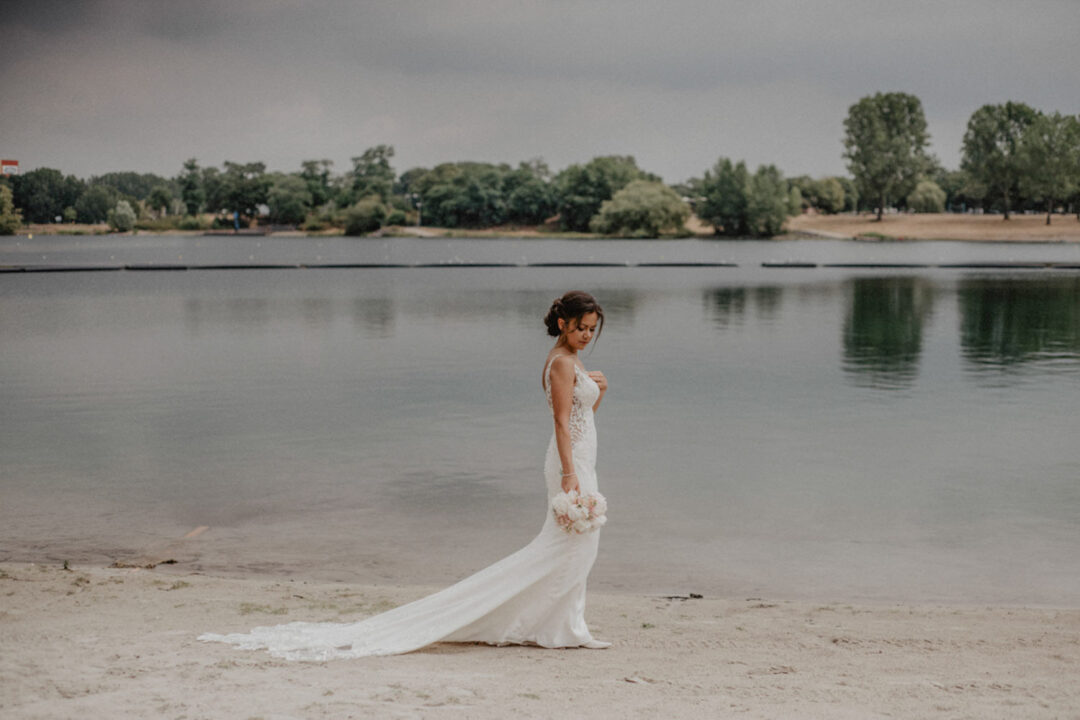 Braut geht am Strand des Fühlinger Sees im Kleid