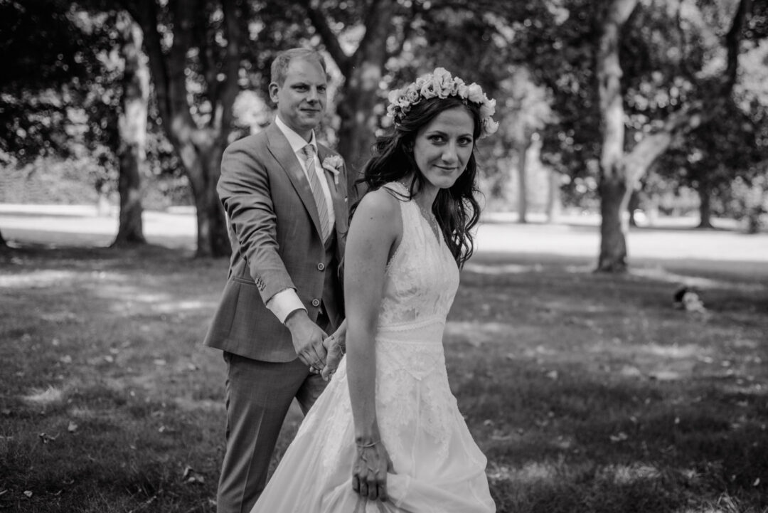 Braut führt Bräutigam lachend beim Hochzeitsshooting