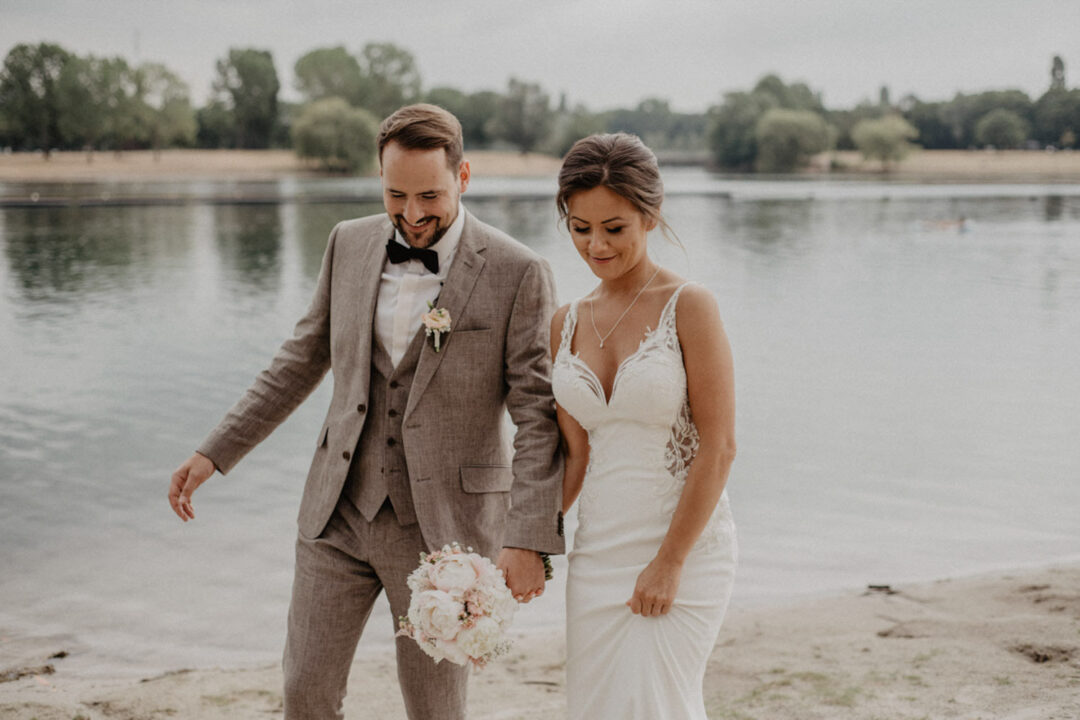 Brautpaar geht Hand in Hand am Fühlinger See entlang