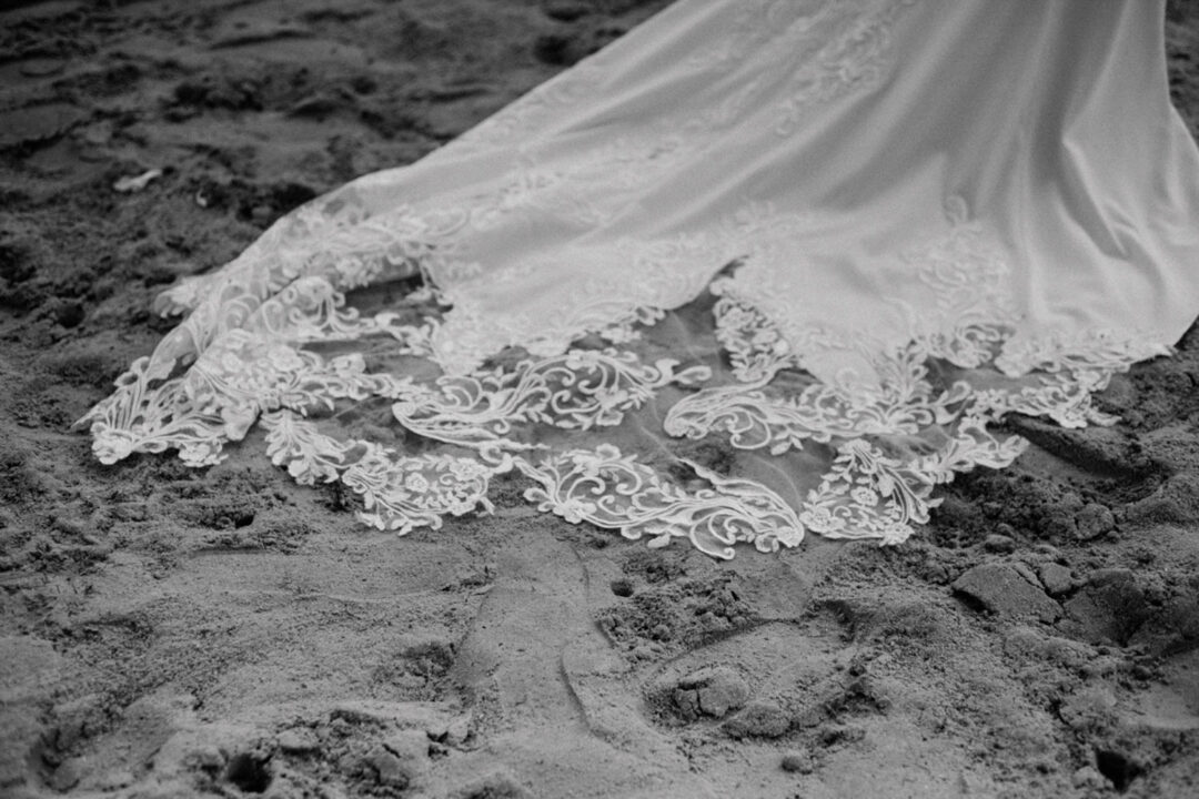 Detailaufnahme vom Spitzenkleid im Sand am Fühlinger See