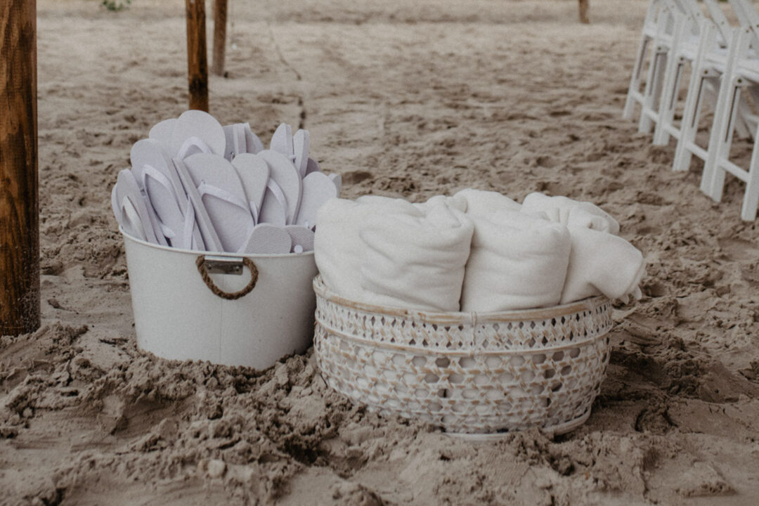 Körbe mit Flipflops und Decken im Sand der Trauungslocation