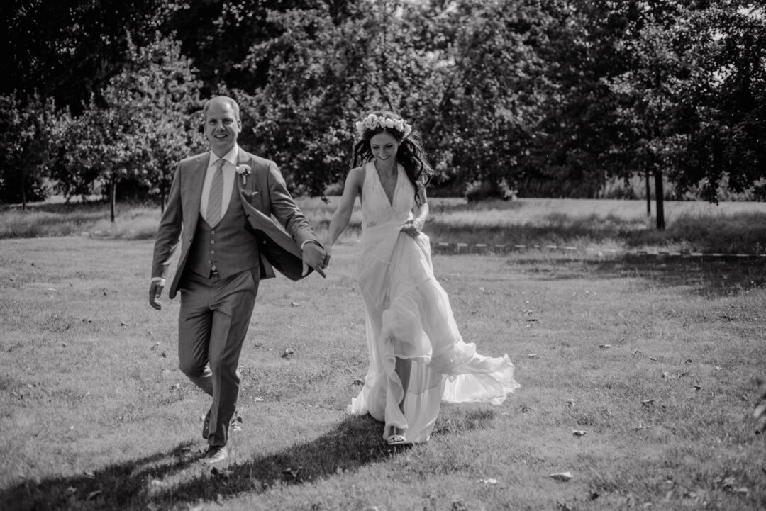 Hochzeitspaar läuft lachend durch den Park