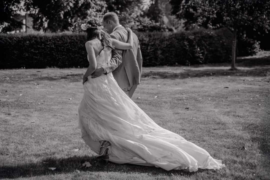 Hochzeitspaar läuft Arm in Arm über die Wiese