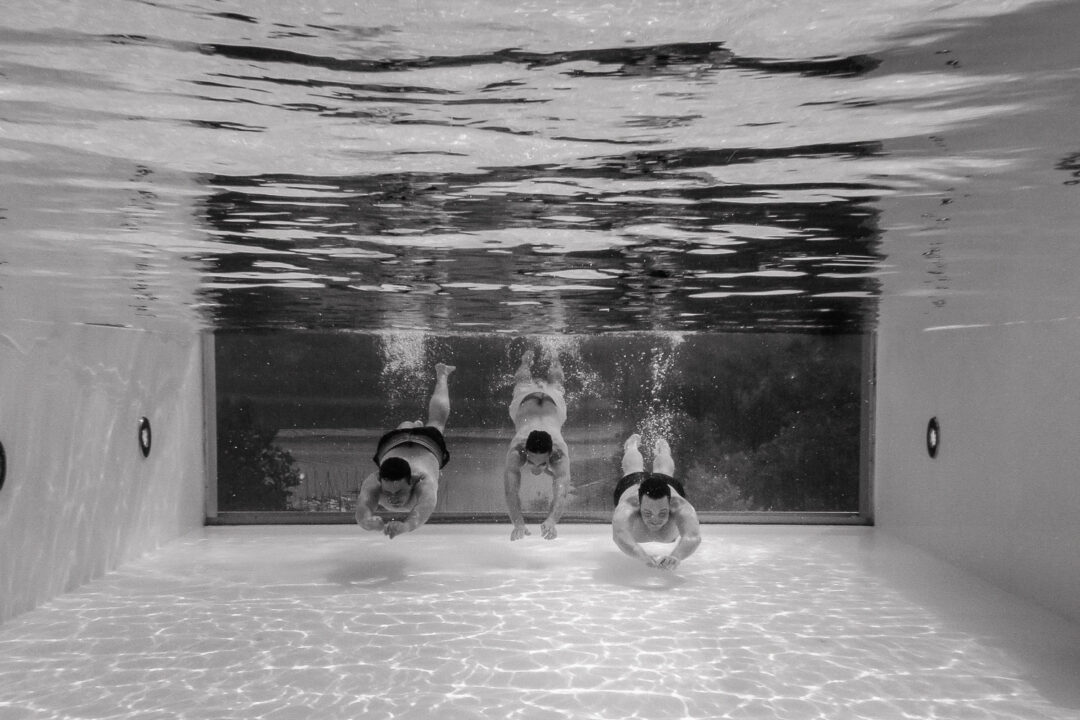 Drei Männer tauchen im Glasrandpool des Hotel Seegarten