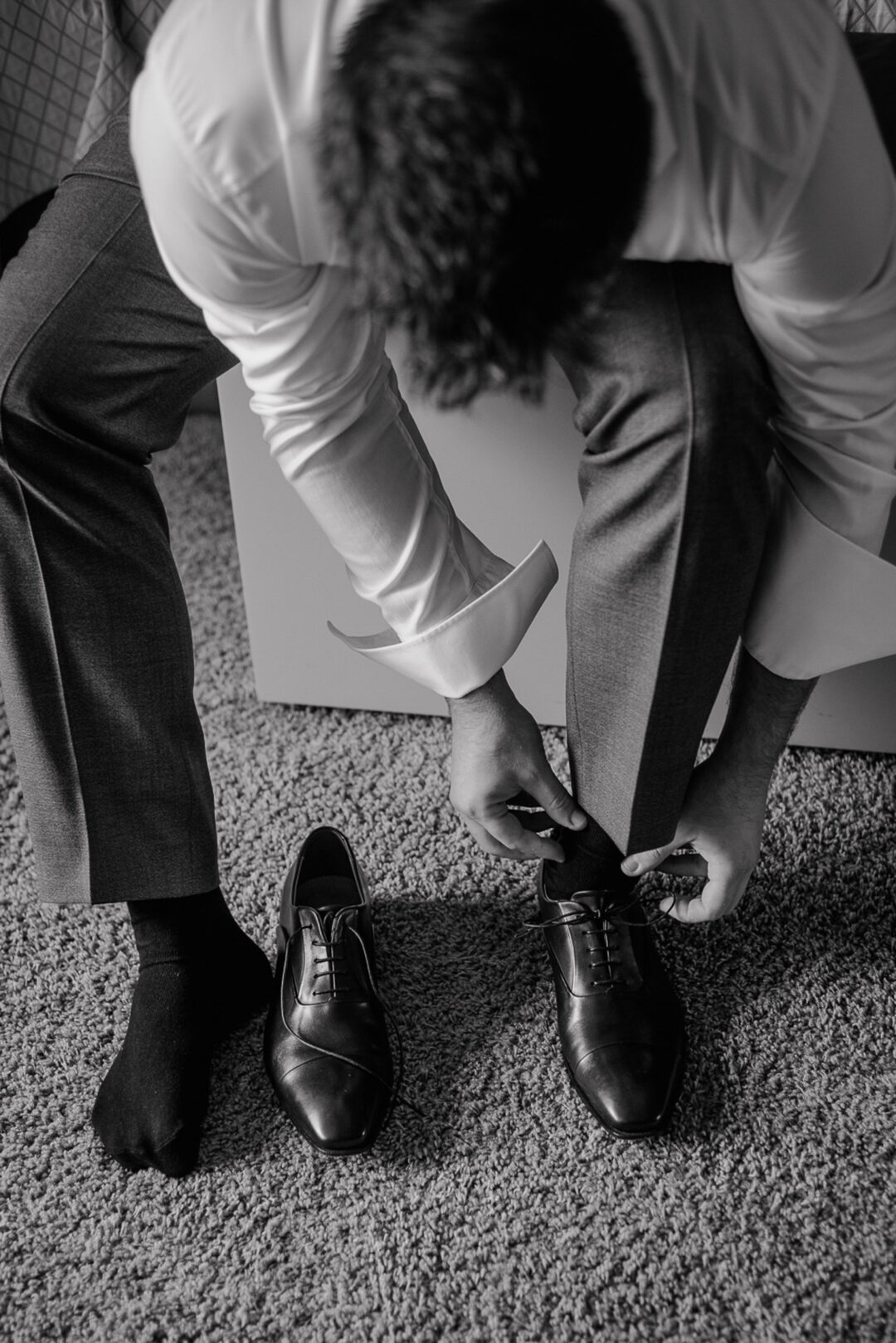 Bräutigam zieht Hochzeitsschuhe im Hotelzimmer an