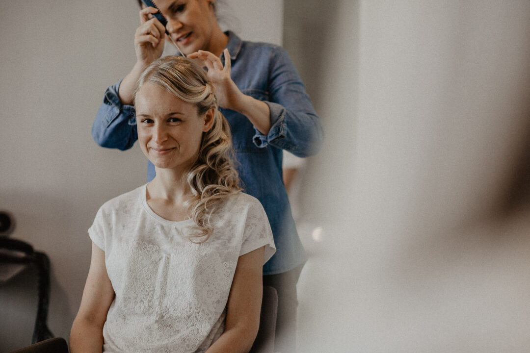 Lächelnde Braut beim Frisieren vor der Hochzeit