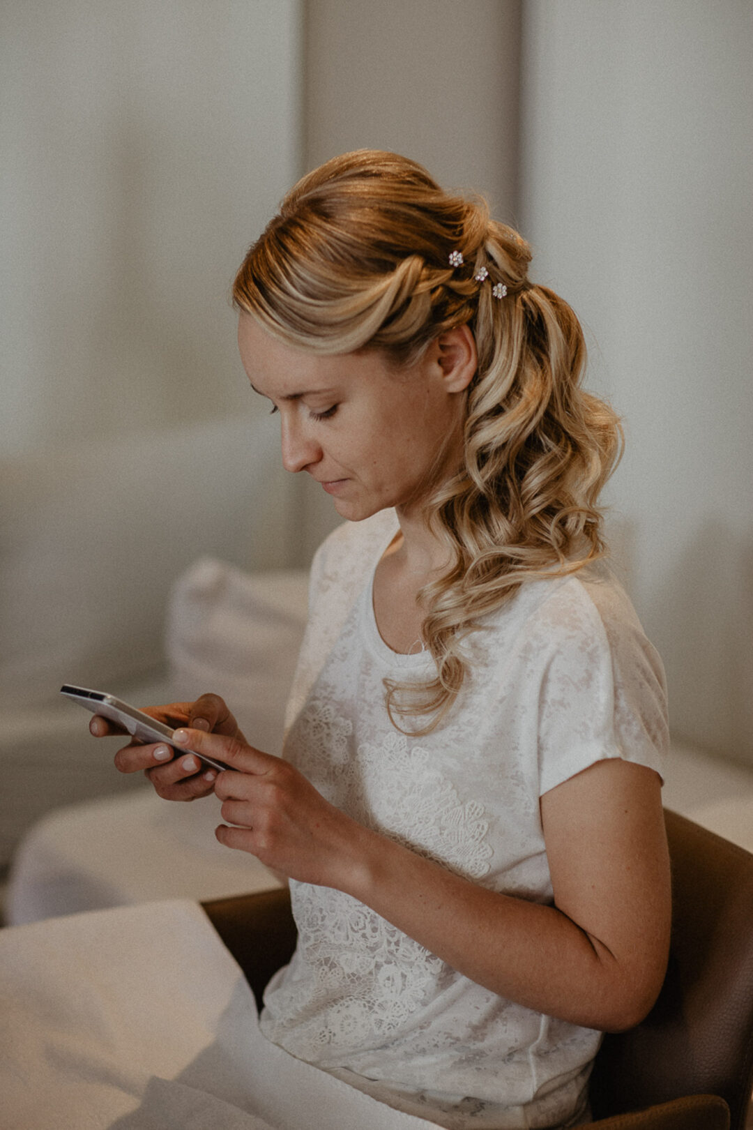 Braut mit gestylten Haaren nutzt ihr Smartphone