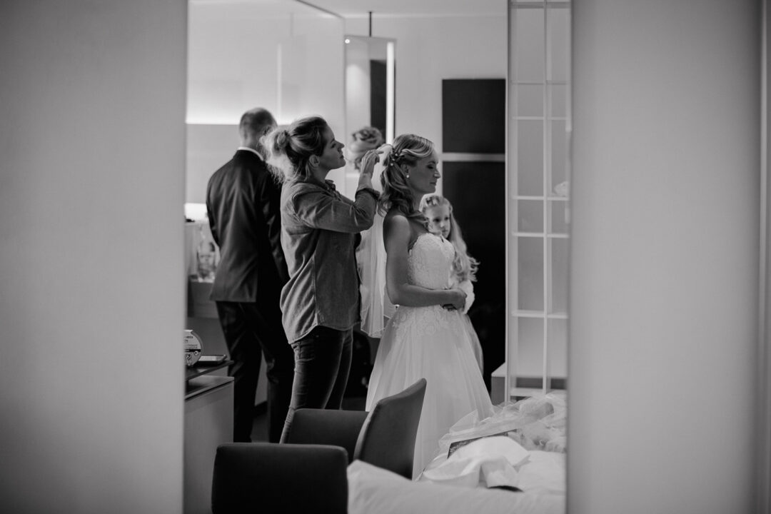 Braut wird frisiert im Hotelzimmer vor der Trauung