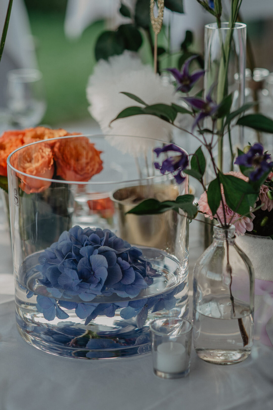 Bunte Blumendeko in Vasen auf Hochzeitstisch