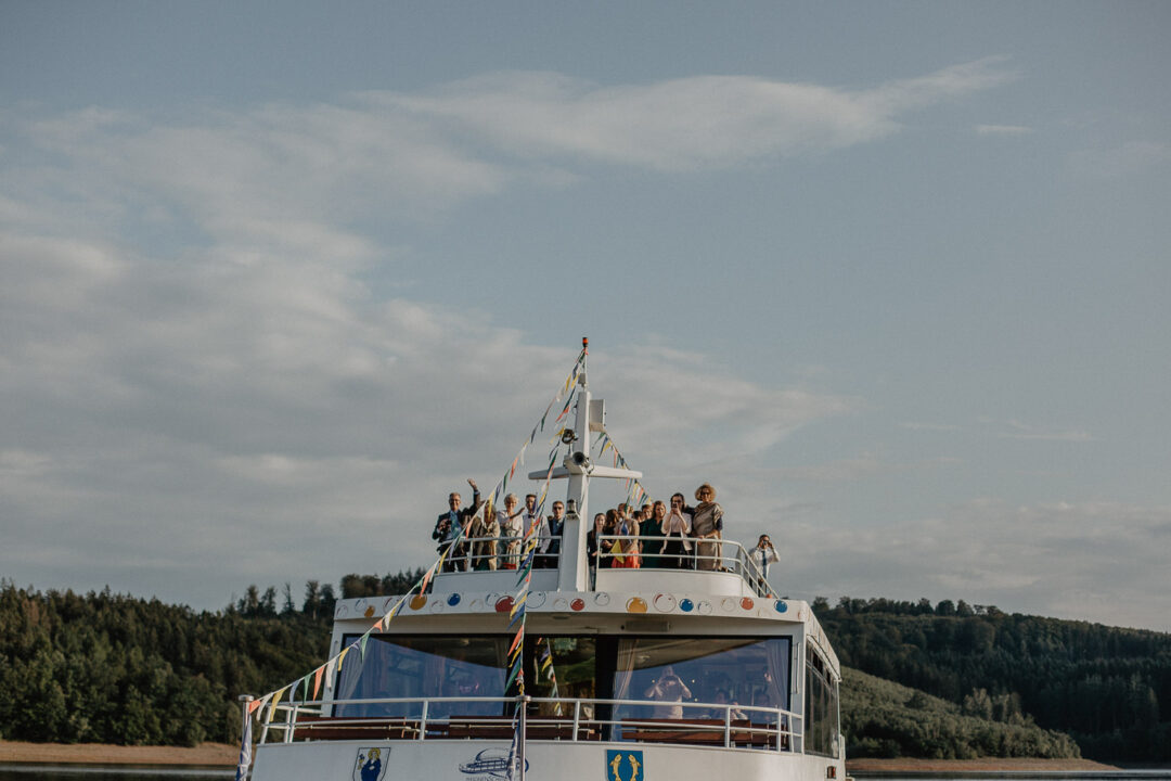 Gäste winken vom Deck des Hochzeitsschiffs