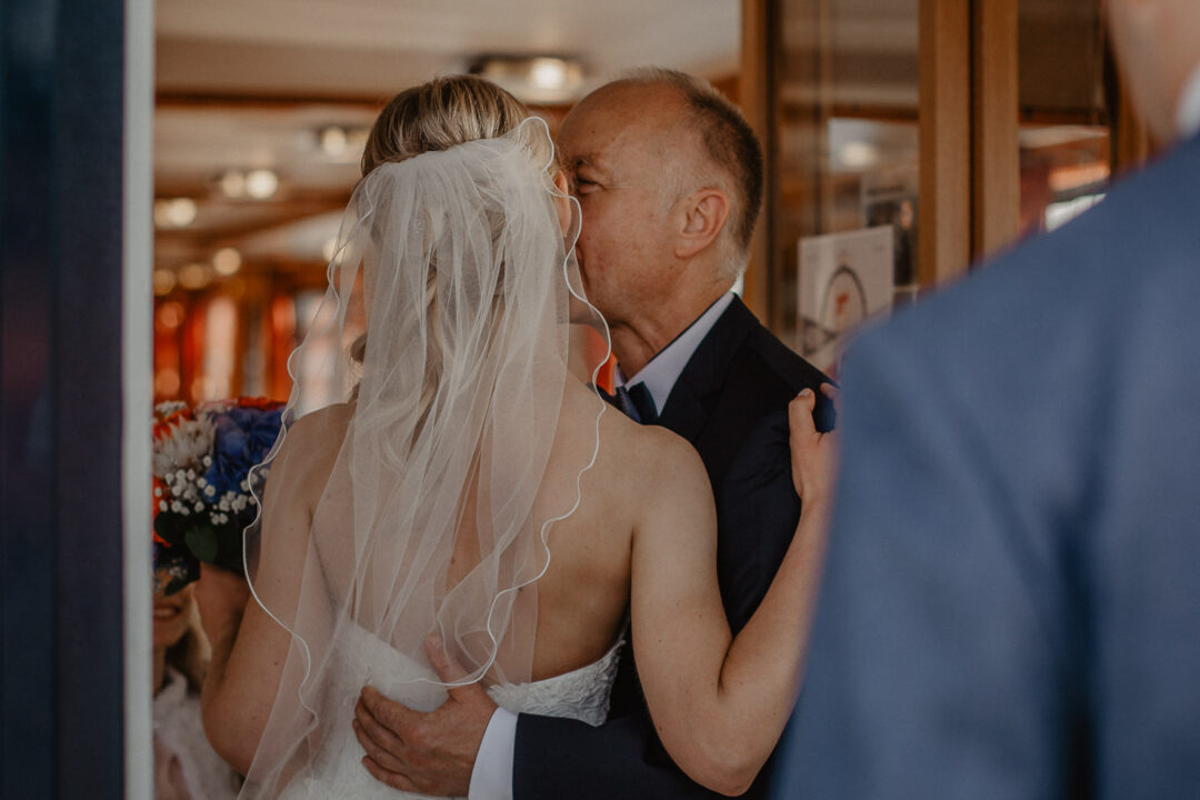 Vater küsst Braut liebevoll bei der Hochzeit