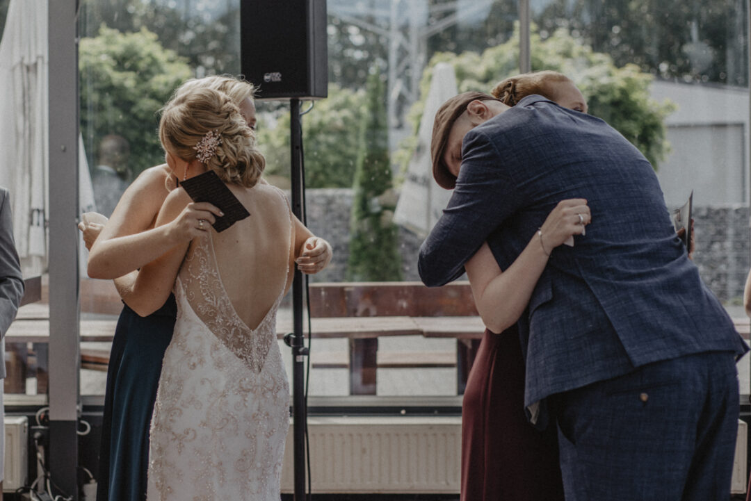 Braut und Bräutigam umarmen ihre Freunde nach den Traureden – ein liebevoller Moment voller Dankbarkeit.