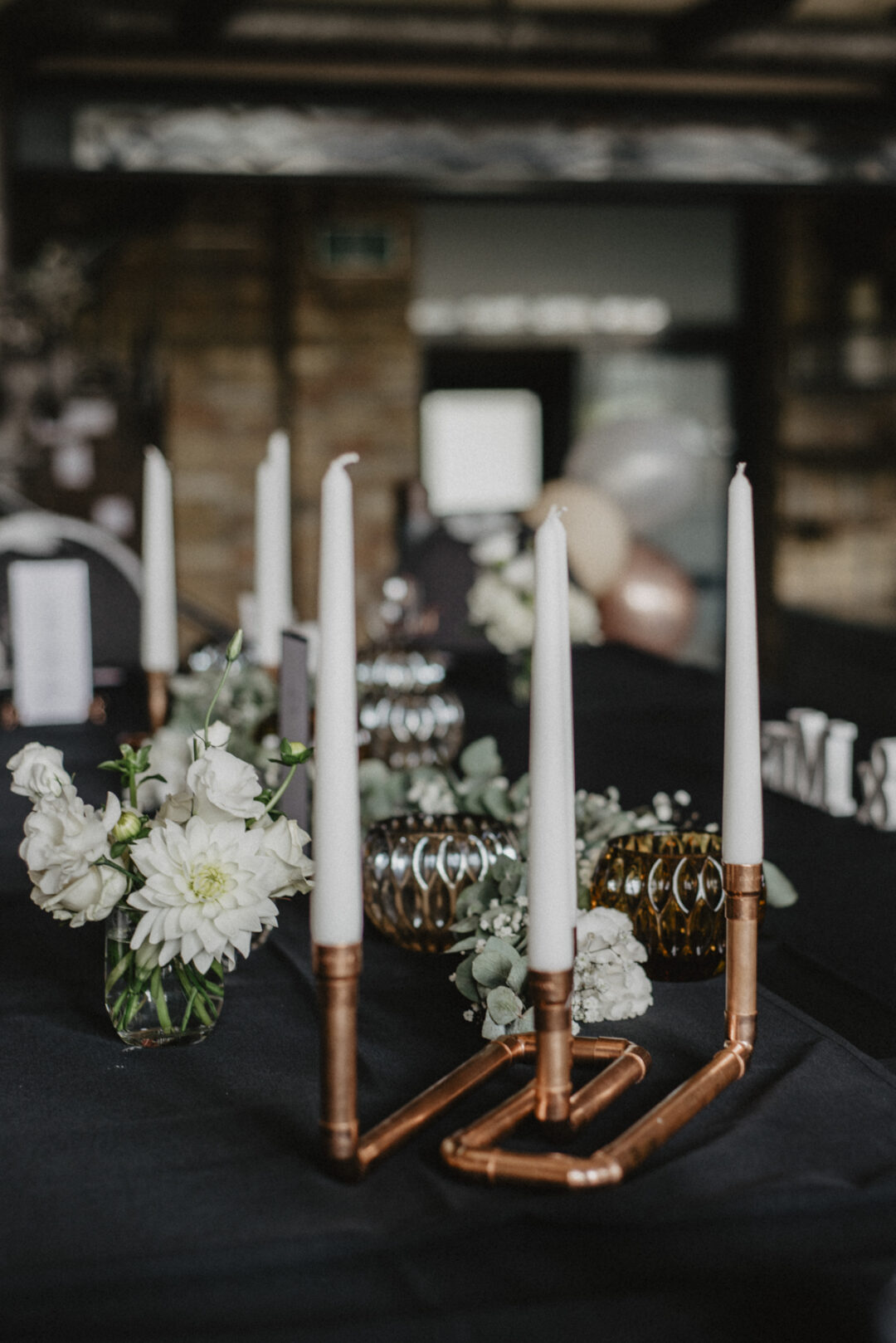 Weiße Blumen und Kupferkerzenständer auf Hochzeitstisch – Kraftwerk Relax