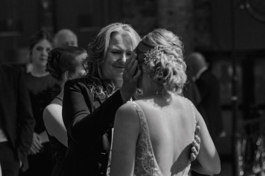 Freundin der Braut legt zärtlich die Hand an das Gesicht ihrer Tochter