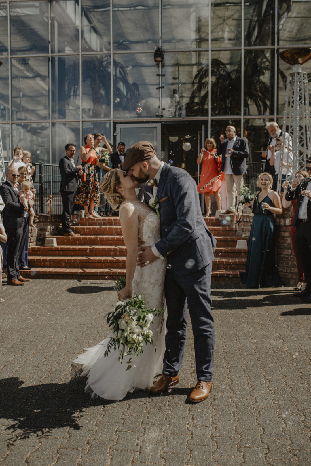 Das Brautpaar küsst sich vor der Glasfassade des Kraftwerk Relax