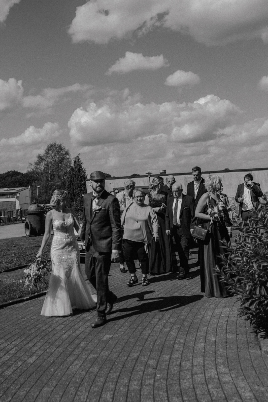 Braut und Bräutigam laufen mit Familie und Freunden über das Gelände