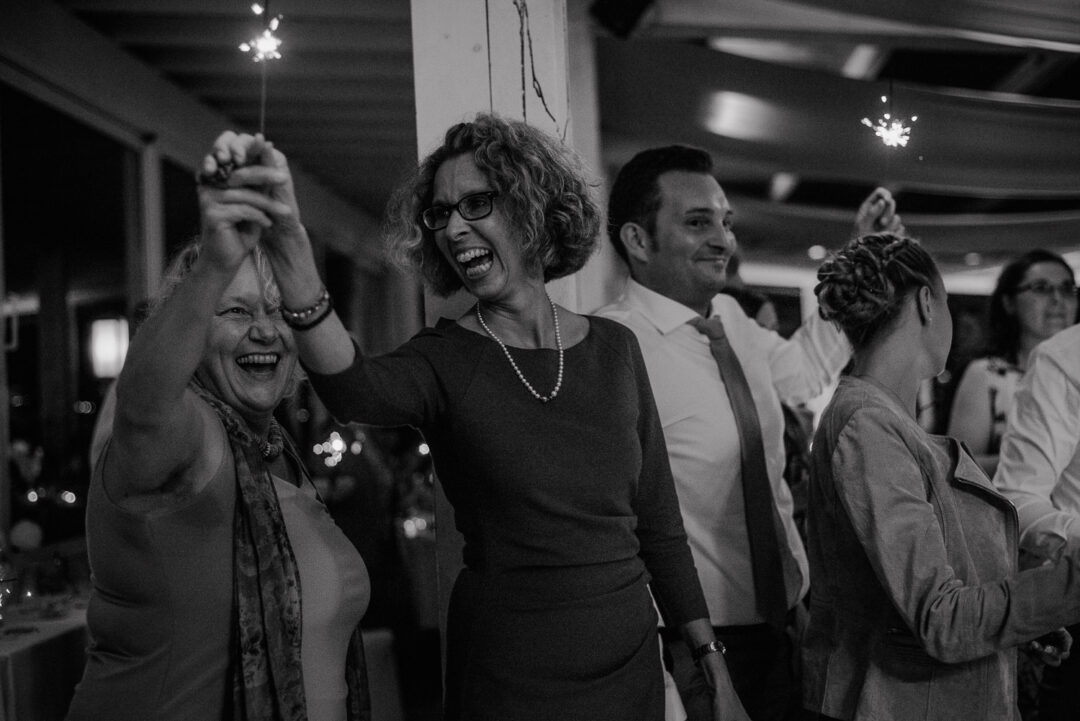 Gäste jubeln mit Wunderkerzen bei Hochzeit