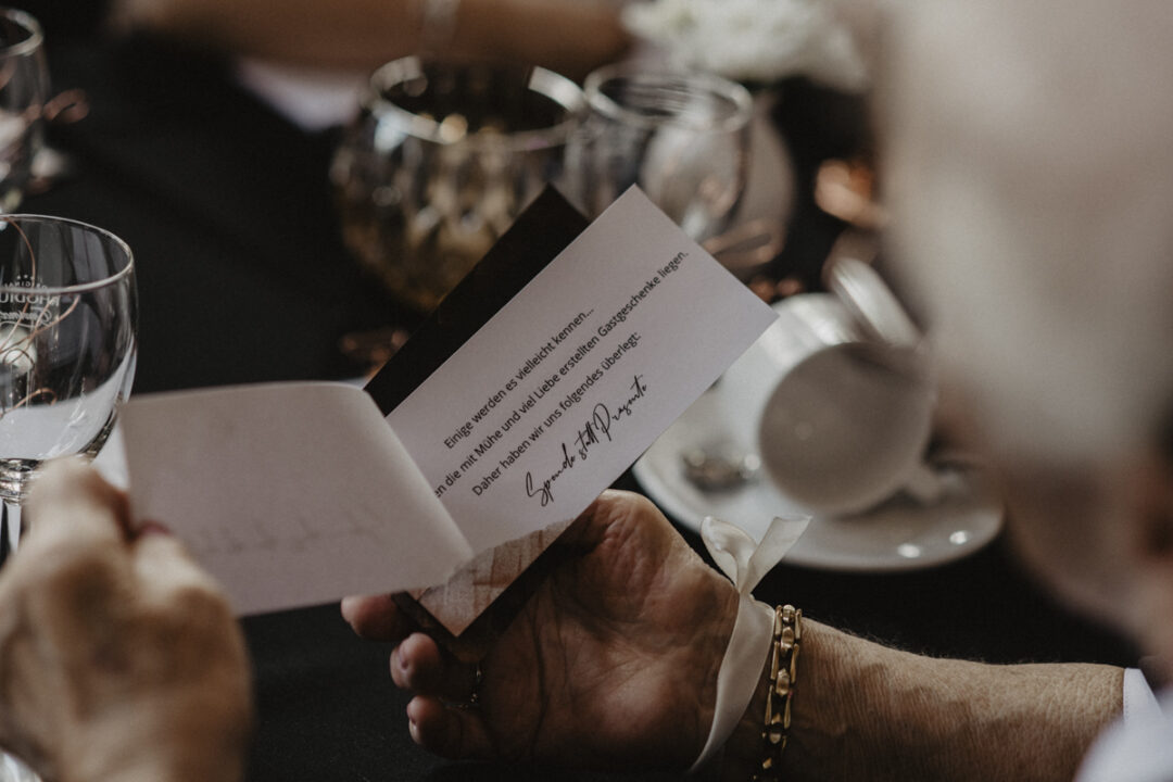 Gast liest Karte mit Hinweis auf Spende statt Geschenk