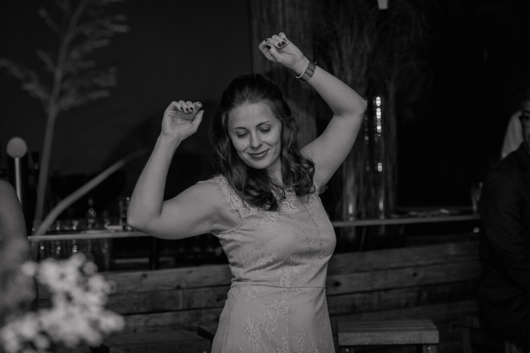 Frau tanzt mit erhobenen Armen bei Hochzeit