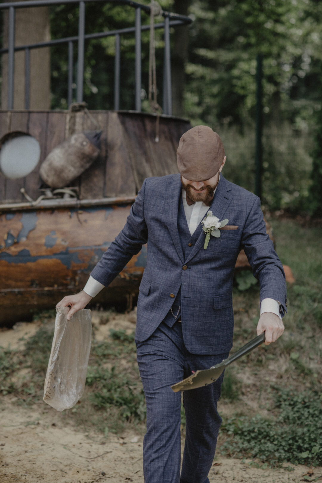 Bräutigam trägt Schaufel und Plastikkapsel im Industrielook