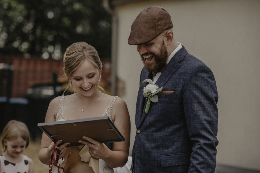 Braut und Bräutigam lachen beim Betrachten eines Geschenks