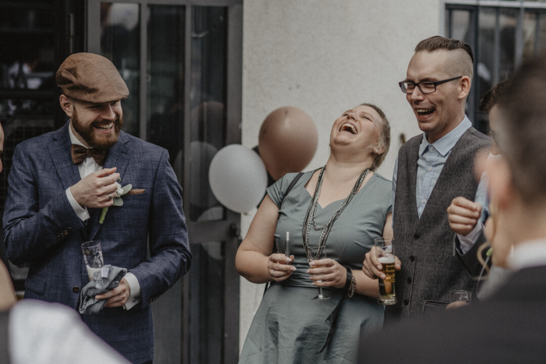 Gäste lachen gemeinsam beim Sektempfang der Hochzeit