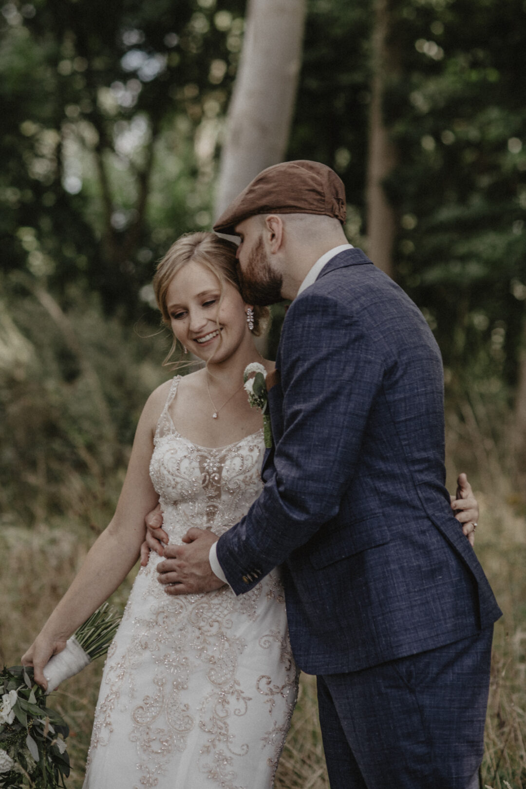 Bräutigam küsst Braut auf die Stirn im Wald