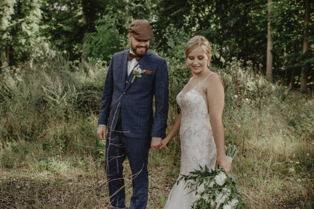 Braut schaut über die Schulter zu ihrem Bräutigam, beide lachen