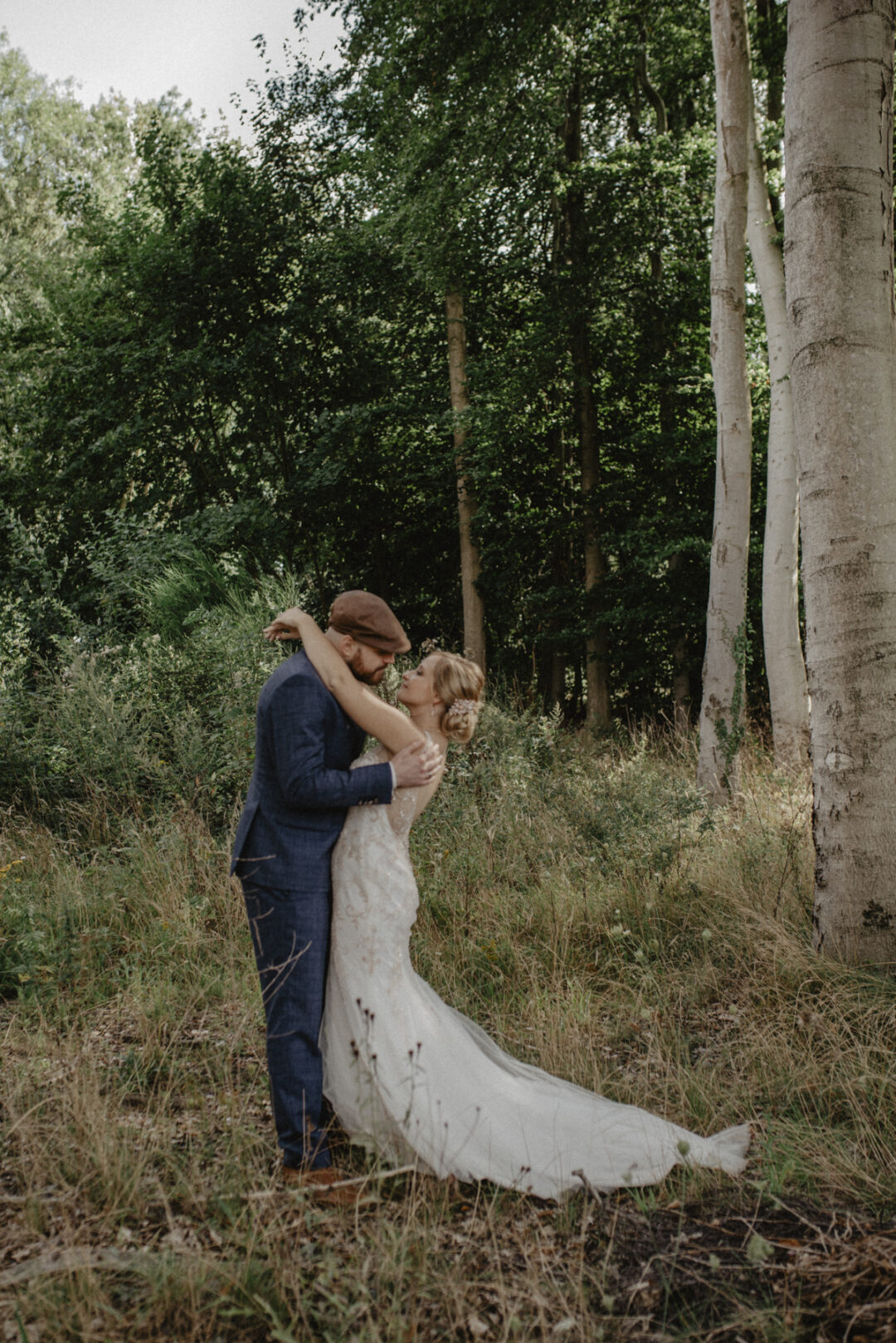 Brautpaar umarmt sich innig inmitten von hohen Bäumen im Sauerland