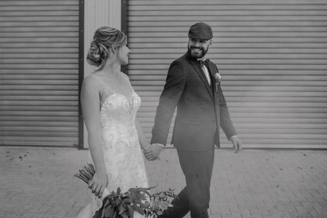 Brautpaar läuft Hand in Hand vor industrieller Kulisse
